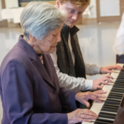 Senior woman playing piano with teen boy